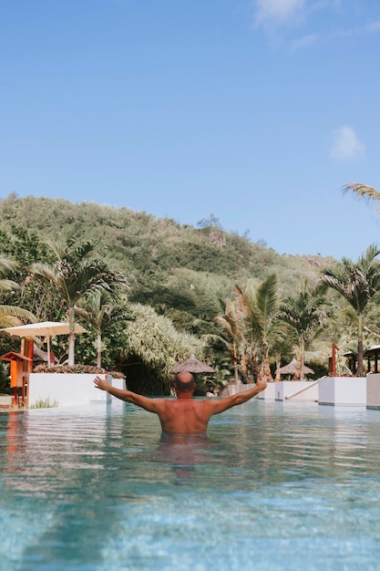 Glücklicher Mann schwimmt in einem Pool auf den Seychellen, das Konzept eines Sommerurlaubs