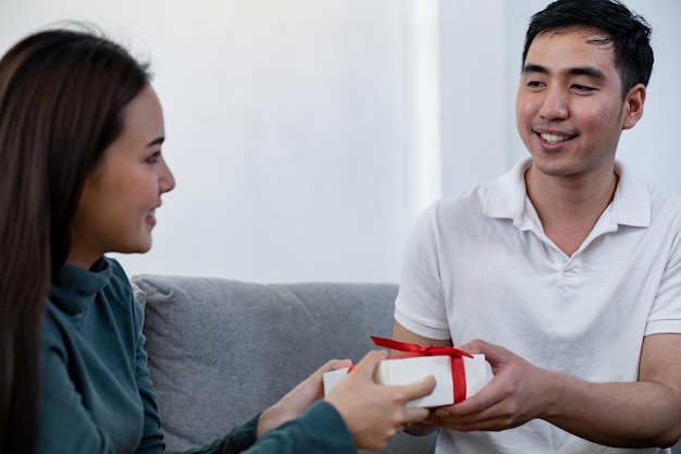 Glücklicher Mann überrascht ihre Freundin mit einer Geschenkbox. Junger Mann überrascht Freundin mit einer Geschenkbox anlässlich des Jahrestages der Liebe.