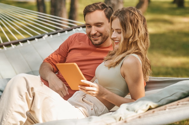 Glücklicher Mann und Frau, die an Tablet interessiert sind