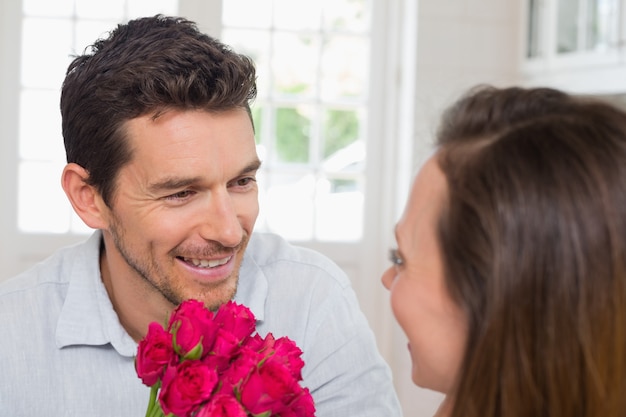 Glücklicher Mann und Frau mit Blumen zu Hause