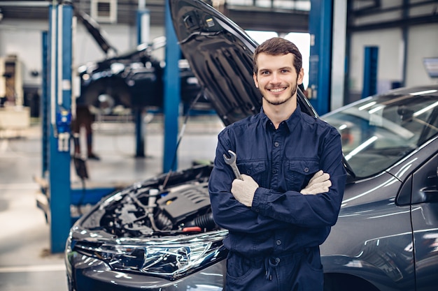 Glücklicher Mechaniker, der am Auto steht