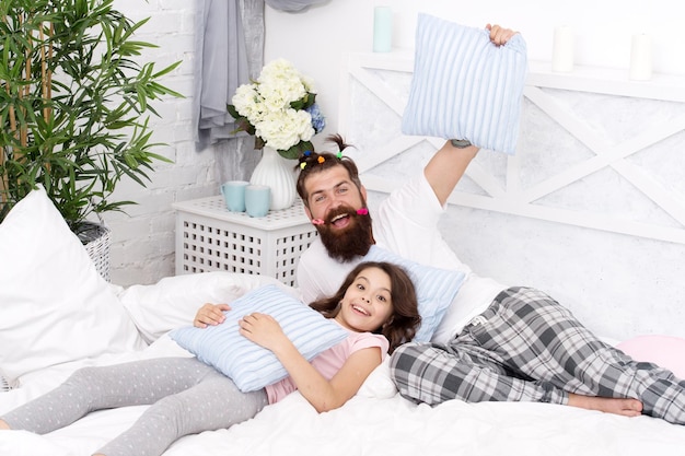 Glücklicher Morgen zusammen, lustige Pyjama-Party, kleines Mädchen mit bärtigem Vater im Bett, Wochenende zu Hause, Vater und Tochter, die Spaß mit der Familie haben. Ich liebe meinen Vater