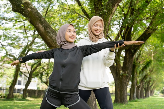 Glücklicher Muslim mit Übungspartner, der zusammen Sport im Freien macht