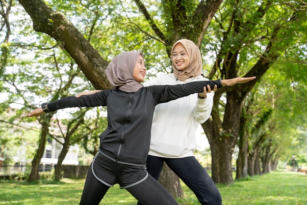 Glücklicher Muslim mit Übungspartner, der zusammen Sport im Freien macht