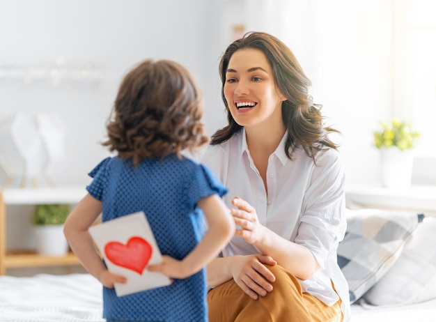 Glücklicher Muttertag Die Tochter des Kindes gratuliert der Mutter und gibt ihr eine Postkarte