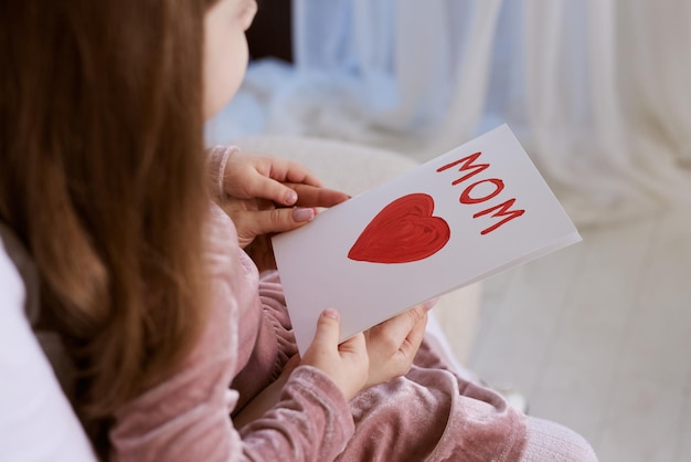 Glücklicher Muttertag Kind Tochter beglückwünscht ihre Mutter und gibt ihr eine Postkarte