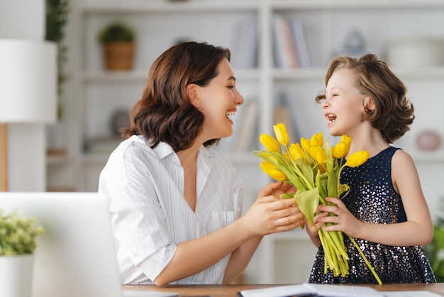 Glücklicher Muttertag Kind Tochter gratuliert Mutter und schenkt ihr Blumen