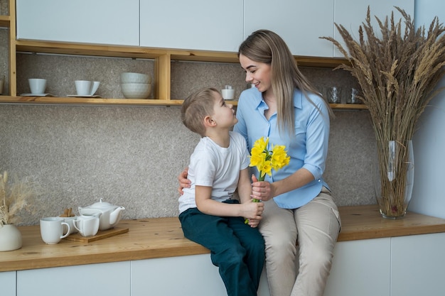 glücklicher muttertag kleiner sohn gibt mama junge blumen gratuliert mama