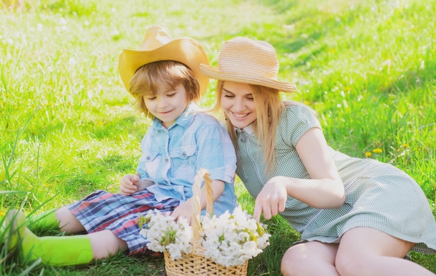 Glücklicher Muttertag mit Sohn beim Picknick Familienmutter mit Kind, das auf dem Gras im Park sitzt