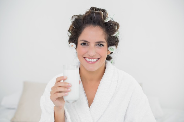 Glücklicher natürlicher Brunette, der Glas Milch hält