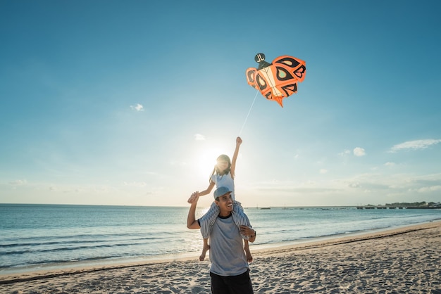 Glücklicher Papa und Tochter fliegen zusammen Drachen am Strand