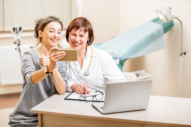 Glücklicher Patient und leitender Arzt, der in der gynäkologischen Praxis ein Selfie-Foto macht