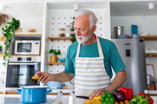 Glücklicher pensionierter älterer Mann, der in der Küche kocht