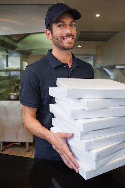 Glücklicher Pizzabote, der viele Pizzakästen hält