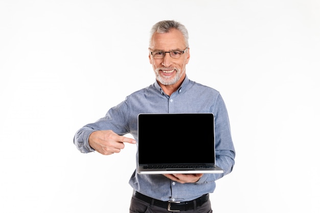 Glücklicher reifer Mann, der auf leeren Bildschirm des Laptop-Computers lokalisiert zeigt
