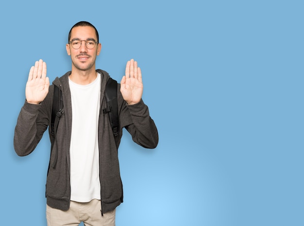 Glücklicher Schüler, der eine Geste des Stopps mit seiner Handfläche macht