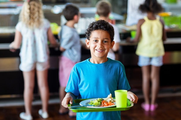 Glücklicher Schüler, der Essenstablett in der Kantine hält