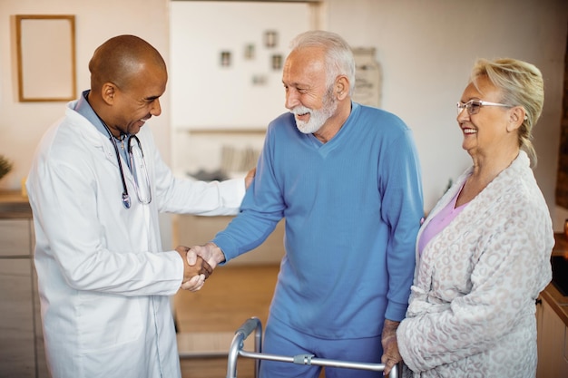 Foto glücklicher schwarzer arzt grüßt älteres paar im pflegeheim