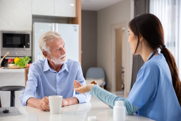 Glücklicher Senior im Ruhestand nimmt eine Pille oder ein Medikament zur Behandlung durch eine junge Ärztin aus der Klinik