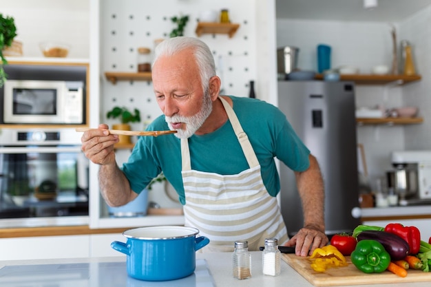 Glücklicher Senior-Mann im Ruhestand, der in der Küche kocht Hobby-Menschen-Konzept für den Ruhestand