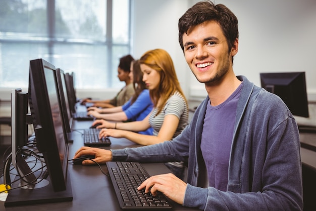 Glücklicher Student in der Computerklasse, die an der Kamera lächelt