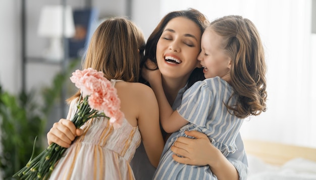 Glücklicher Tag Kindertöchter gratulieren Mutter und schenken ihr Blumen