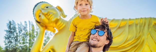 Glücklicher touristenvater und sohn auf dem hintergrund des liegenden buddha-statuenbanners im langen format