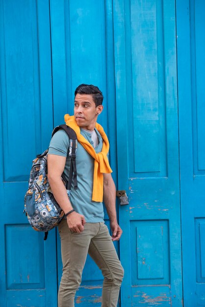 Glücklicher und junger lateinischer Mann, der durch eine blaue Tür steht Panama