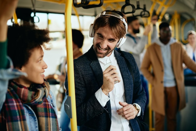 Glücklicher Unternehmer, der Spaß hat, während er Musik über Kopfhörer in einem Bus hört