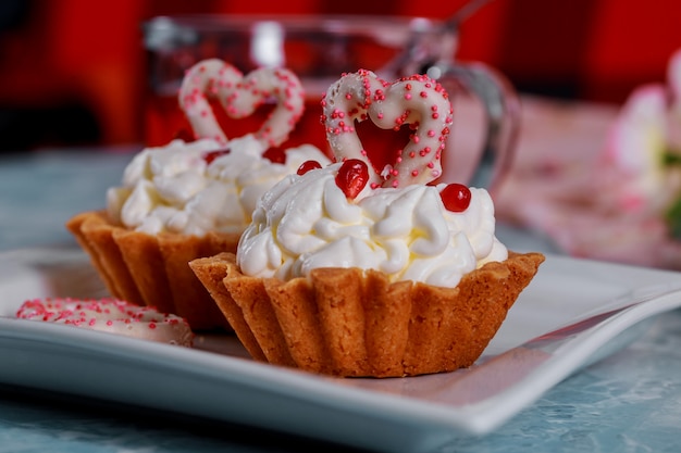 Glücklicher Valentinstag wird auf dekorative kleine Kuchen mit Valentinstagkonzept geschrieben