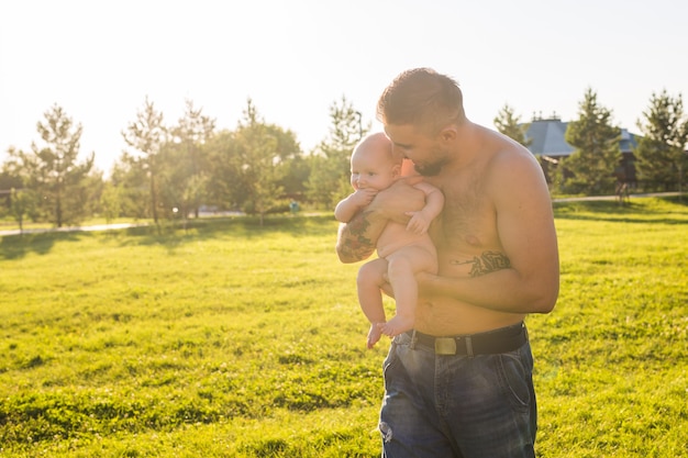 Glücklicher Vater, der Babysohn auf Naturkonzept des glücklichen Familienvaters Tag und des Kindes hält