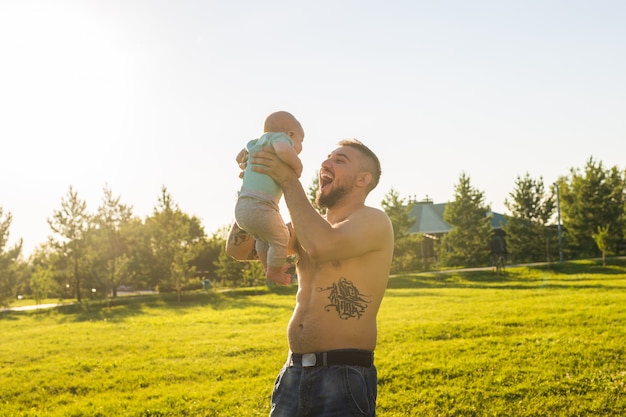 Glücklicher Vater, der Babysohn hält und Baby in die Luft wirft. Konzept der glücklichen Familie, des Vatertags und des Kindes.