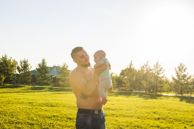 Glücklicher Vater, der Babysohn hält und Baby in die Luft wirft. Konzept der glücklichen Familie, des Vatertags und des Kindes