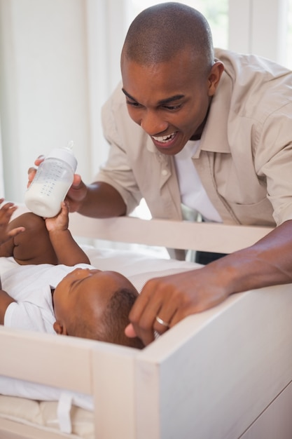 Glücklicher Vater, der Flasche für Babysohn hält