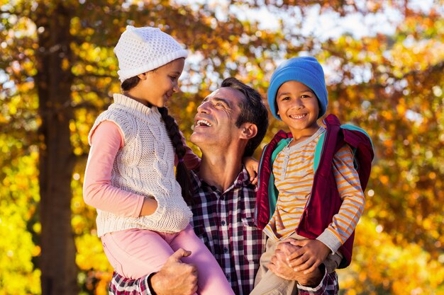 Glücklicher Vater, der Kinder im Park trägt