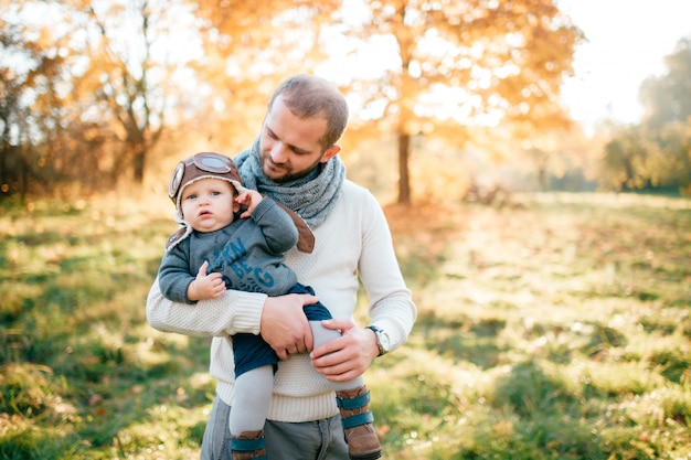 Glücklicher Vater, der mit seinem entzückenden Kind im Herbstpark aufwirft