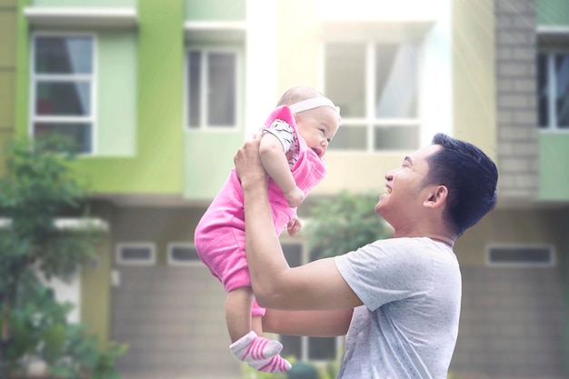 Glücklicher Vater hebt sein Baby im Freien hoch