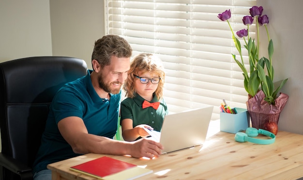 Glücklicher Vater hilft seinem Schulsohn beim Lernen mit Laptop zu Hause, Wissen