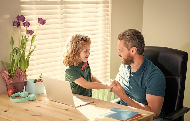 Glücklicher vater hilft seinem schulsohnkind in der brille, mit der computerfamilie zu hause zu lernen