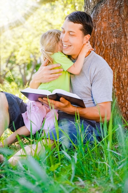 Glücklicher Vater mit einem Kind, das ein Buch über die Natur der Bibel liest