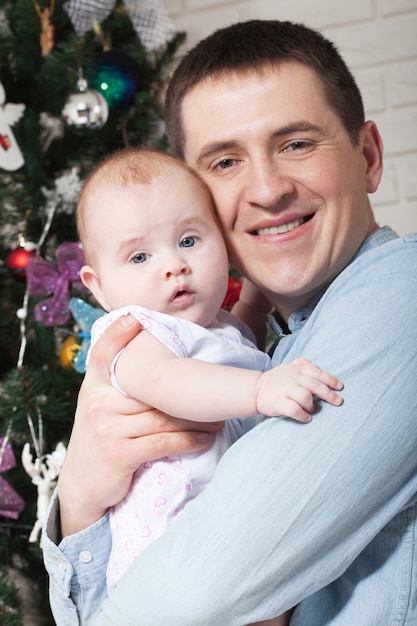 Glücklicher Vater mit kleinem Baby nahe Weihnachtsbaum