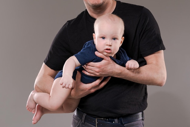 Glücklicher Vater mit seinem kleinen Sohn im Studio auf Hintergrund Fürsorglicher kaukasischer Vater