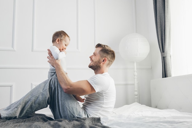 Foto glücklicher vater mit seinem sohn, der zu hause auf dem bett spielt