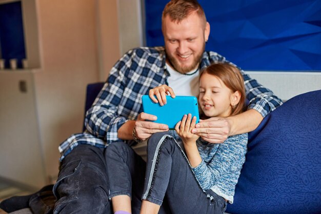 Glücklicher Vater mit Tochter mit Tablet-Computer im Wohnzimmer auf dem Sofa zu Hause