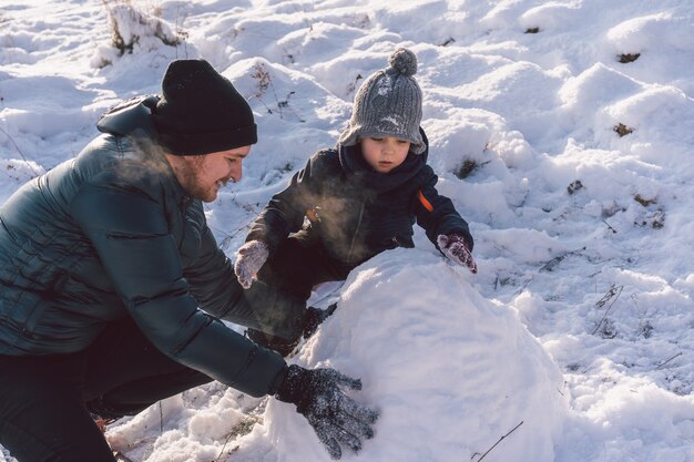 Glücklicher Vater und kleiner Junge, die mit Schnee spielen