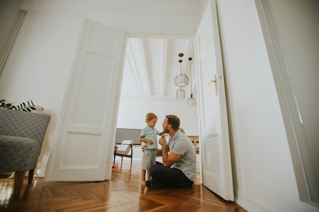 Glücklicher Vater und kleiner Sohn, die zu Hause Spaß spielt und hat