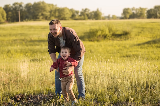 glücklicher Vater und kleiner Sohn ruhen auf dem Feld des Federgrases