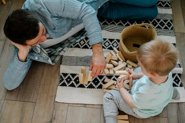 Glücklicher Vater und Kleinkind Junge Kind kleiner Sohn spielt mit Holzklötzen im Kinderzimmer zu Hause