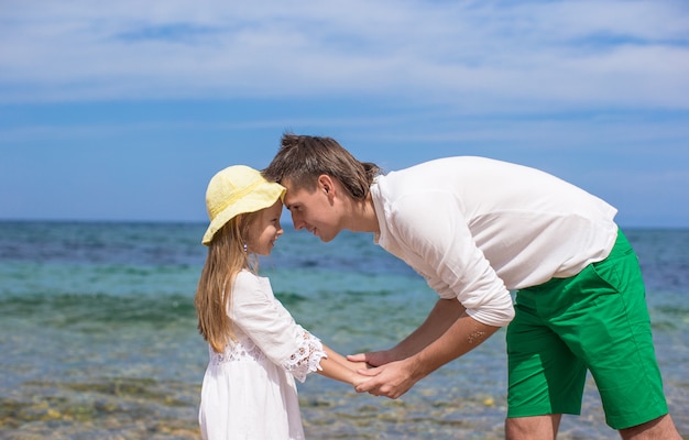 Glücklicher Vater und seine entzückende kleine Tochter am Strand am sonnigen Tag