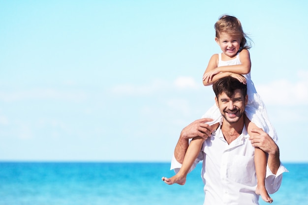 Glücklicher Vater und seine süße kleine Tochter am Sonnenstrand